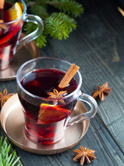 Two glasses of mulled red wine with cinnamon, orange and star anise on wooden table. Christmas and New Year drink.