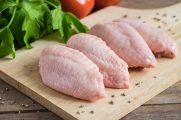 Raw chicken wings on wooden cutting board