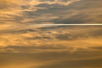 trail from the plane in the sky at sunset