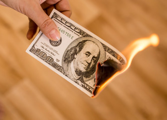 one hundred dollars burn in flames in hand