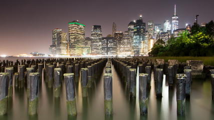 New York - Manhattan Skyline, skyscrapers seen from Brooklyn Bridge Park with wooden piles of Pier One in the East River