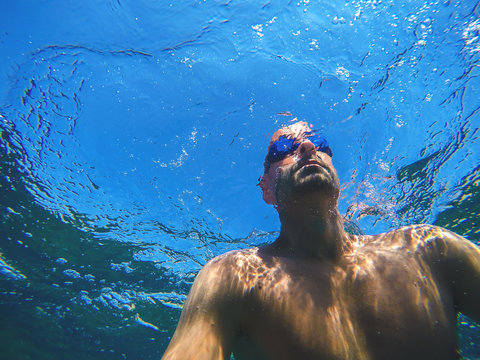 Underwater photo of a young man swimming in the turquoise exotic sea for summer vacation.
