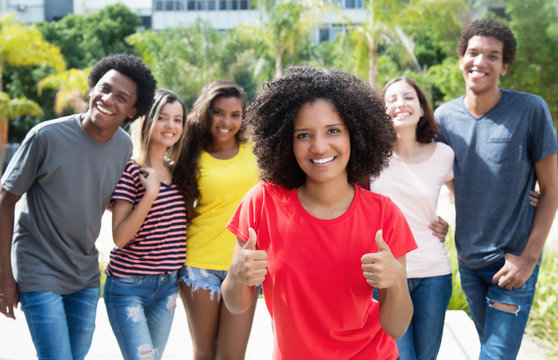 Pretty african american woman showing thumb up with international friends