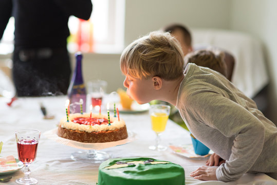 Auspusten der Geburtstagskerzen auf dem Kuchen zum 8. Geburtstag