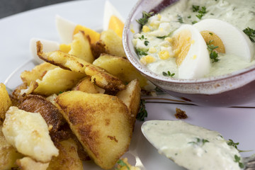 Teller mit grüner Sauce, Bratkartoffeln und Eiern