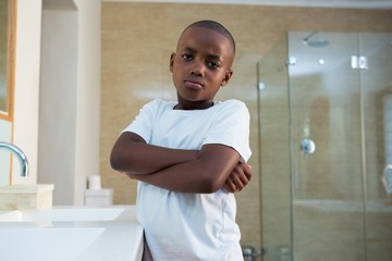 Portrait of boy standing by sink with arms crossed