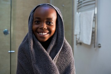 Portrait of smiling boy wrapped in gray towel