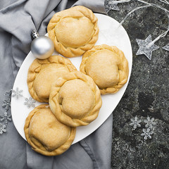 Comfortable food for the whole family. Homemade mini pies made from fresh simple dough with seasonal berries, served with honey. Top view on a gray grunge background.