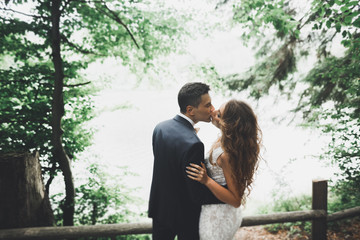 Newly married couple running and jumping in park while holding hands