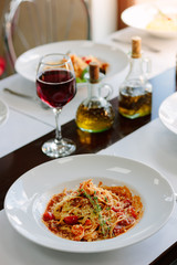 Italian traditional pasta with tomatoes and seafood on restaurant table.