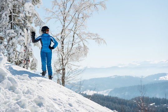 Full length shot of a happy female skier resting the slope with her skis in the mountains at winter ski resort copyspace