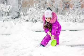 Fototapeta na wymiar Little kid girl shoveling snow on home drive way.