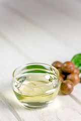 Natural and organic macadamia oil on a white wooden table.