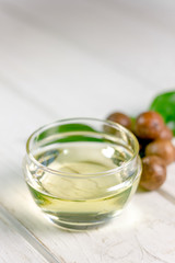 Natural and organic macadamia oil on a white wooden table.
