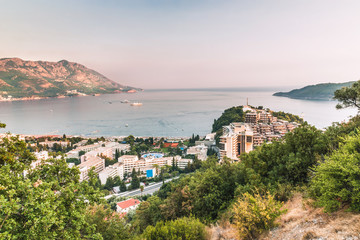 Obraz premium View of the beautiful bay, hotels and crowded beaches of the resort town of Becici in the rays of the sunset, Budva Riviera, Montenegro.
