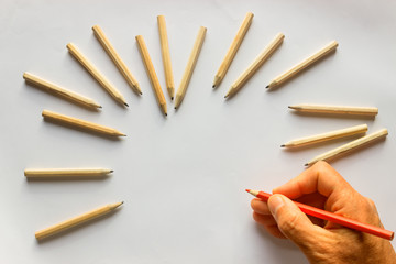 Hand holding red pencil. Around plenty identical  pencils .Leadership, uniqueness, independence,...