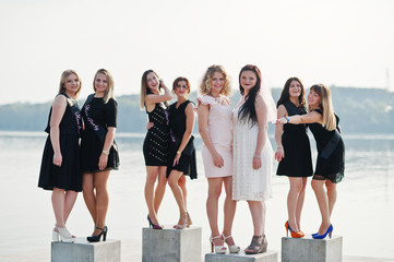 Fototapeta na wymiar Group of 8 girls wear on black and 2 brides at hen party against sunny beach.