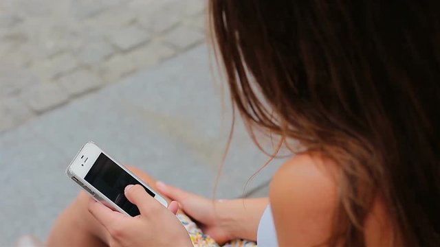 Young girl chatting with friends using smartphone. Outdoor, summer.