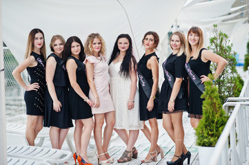 Group of 8 girls wear on black and 2 brides at hen party having fun at pier on beach side.