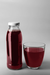 Bottle and glass with juice on light background