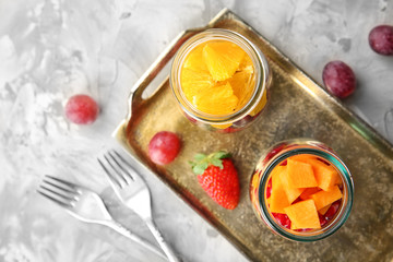 Delicious fruit salads in jars on metal tray