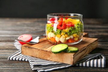 Delicious vegetable salad in jar on wooden board