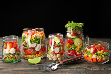 Glassware with fresh vegetable salads on wooden table