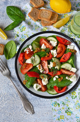 Vitamin salad with tomatoes, spinach and feta cheese on betonnoom background. Top view.