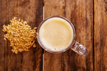 Above view of glass of beer with wheat in the base on a wooden table in a wooden background