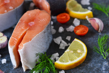 Fresh raw salmon steak with lemon and salt on black marble background