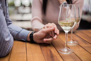 Young couple holding hands at the cafe, closeup.