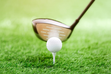 Golf club and ball on green grass