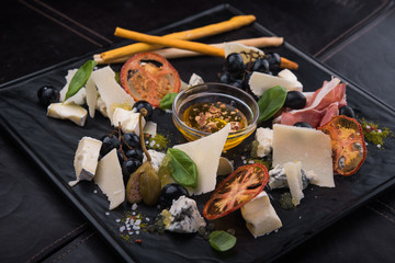 tasty cheese plate with sauce, prosciutto