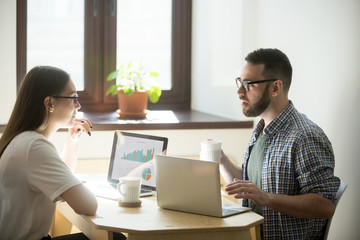 Two coworkers discussing new working concept in office. Millennial businesswoman and businessman...