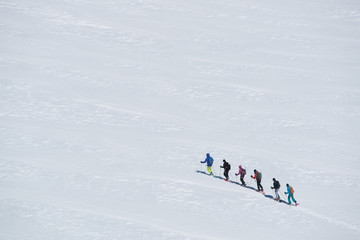 Fototapeta na wymiar group of people exploring glacier or snowy land walking with snowshoes. Europe Alps Mont Blanc massif mount. Winter sunny day, snow, wide shot.Exploring and travelling