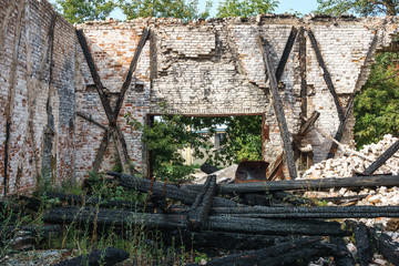 Old abandoned ruined building with burned logs of wood
