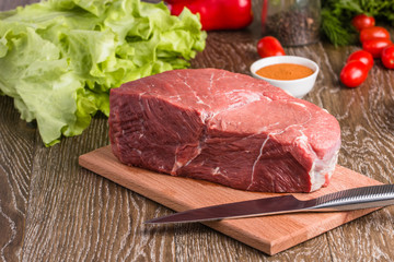 raw beef steak on wooden cutting board