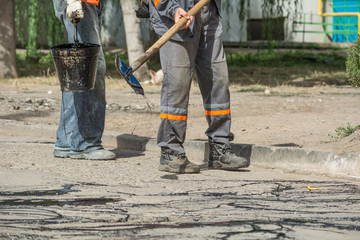 Road repair. Work details, workers pour resin road surface to cover the asphalt