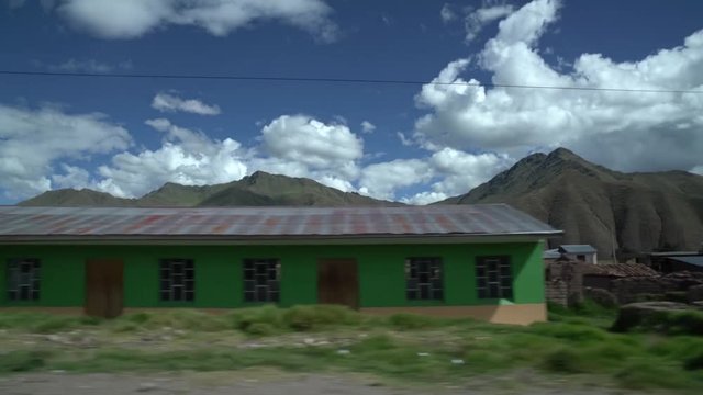 Drive by of countryside of Peru, outside of Cusco. Hills in background town buildings in foreground.