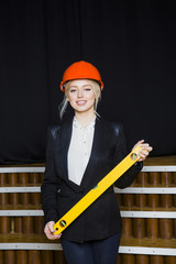 Beautiful blonde businesswoman with application tier at loft office in orange construction helmet and suit.