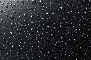 Water drops on black surface, abstract background.