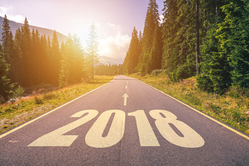 Empty asphalt road and New year 2018 concept. Driving on an empty road in the mountains to upcoming 2018 and leaving behind old 2017. Concept for success and passing time.