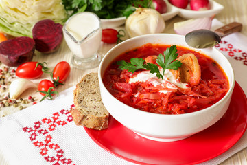 Traditional Ukranian soup borsch on a white napkin embroidered in Ukrainian style.