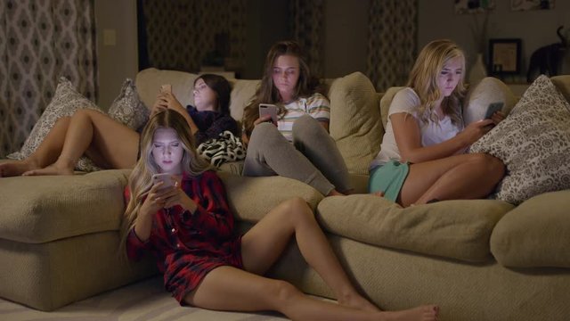 Medium shot of girls distracted by cell phones at slumber party / Cedar Hills, Utah, United States