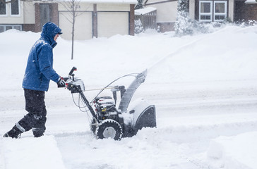 Man Removing Snow with a Snowblower in a Suburban Neighborhood
