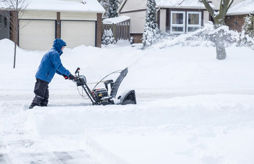 Man Removing Snow with a Snowblower in a Suburban Neighborhood