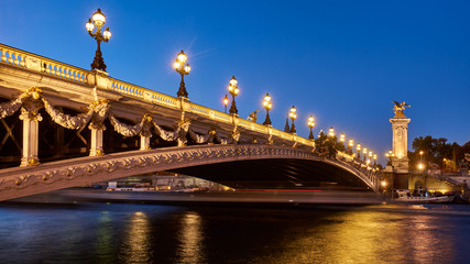 Panoramablick auf die Brücke Pont Alexandre III, die abends mit der Seine beleuchtet wird. 8. Arrondissement, Paris, Frankreich