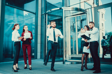 A young male businessman is enjoying a successful deal on the background of office workers. Demonstration of positive emotions and gestures. Career. Success. Shows a thumbs-up.