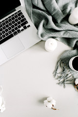 Modern home office desk with laptop, plaid, candles, cotton balls. Flat lay, top view holiday composition.