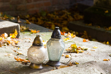 Votive candles at the grave with autumn leaves.